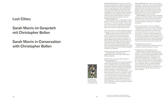 Eine Doppelseite aus einer Publikation mit dem Titel Lost Cities: Sarah Morris im Gespräch mit Christopher Bollen. Der Text des Interviews ist in zwei Spalten auf Deutsch und Englisch abgedruckt. Auf der rechten Seite ist ein kleines Schwarz-Weiß-Foto von Art Buchwald beim Tennis zu sehen.