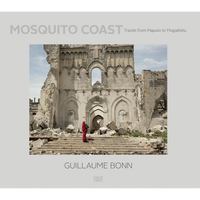 Das Buchcover von Mosquito Coast von Guillaume Bonn zeigt eine Person in einem leuchtend roten Gewand, die eine Steintreppe zur Ruine der Kathedrale von Mogadischu hinaufsteigt. Die Fassade des Gebäudes ist stark zerstört und von Trümmern übersät.