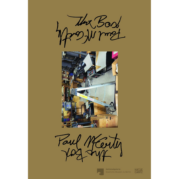 Das olivgrüne Buchcover von Paul McCarthys The Box zeigt in der Mitte ein Foto eines vollgestellten Ateliers, umgeben von handschriftlichem Text.