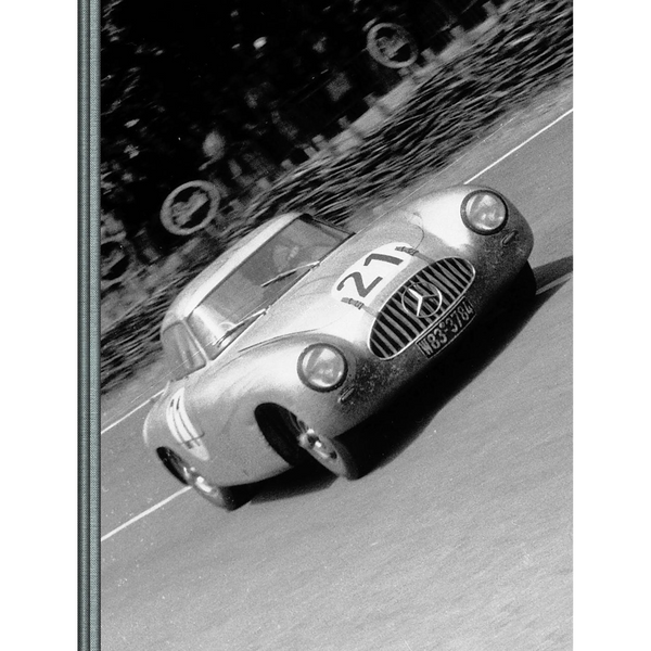 Ein Schwarz-Weiß-Foto eines historischen Mercedes-Rennwagens mit der Nummer 21 in voller Fahrt auf einer Rennstrecke.