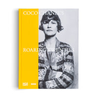 Ein Buch mit dem Titel Coco Chanel's Roaring Twenties, dessen Cover ein Schwarz-Weiß-Porträt von ihr mit verschränkten Armen neben einem leuchtend gelben Buchrücken zeigt.