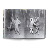 Ein aufgeschlagenes Buch zeigt eine Doppelseite mit Schwarz-Weiß-Fotografien von Tänzern im Stil der 1920er Jahre. Links macht eine Tänzerin einen einarmigen Handstand, während ein Mann ihr hochgestrecktes Bein hält. Rechts posieren zwei Tänzerinnen in ähnlichen Kostümen eng aneinandergelehnt.