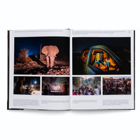 Ein aufgeschlagenes Buch zeigt eine Fotoreportage auf einer Doppelseite über das Zusammenleben von Menschen und Elefanten in Sambia. Links oben steht ein großer Elefant nachts auf einer Müllhalde. Rechts daneben sitzt ein Mann am Steuer eines Autos. Darunter sind vier kleinere Bilder von Menschen, die Elefanten nachts und bei Tag beobachten.