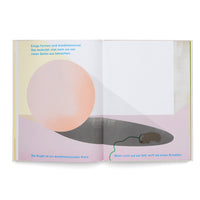 Ein aufgeschlagenes Kinderbuch zeigt eine Illustration über zwei Seiten. Links ist eine große, rosafarbene Kugel zu sehen, die einen dunklen Schatten nach rechts wirft. In diesem Schatten schläft eine kleine, braune Maus mit einem langen, grünen Schwanz. Die Szene wird von deutschem Text begleitet, der dreidimensionale Formen erklärt.