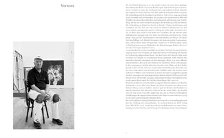 Eine Buchseite mit einem Schwarz-Weiß-Foto auf der linken und einem Textblock auf der rechten Seite. Das Foto zeigt den Künstler Georg Baselitz, der in seinem Atelier auf einem Stuhl sitzt. Er trägt eine Kappe, ein dunkles Poloshirt und eine helle Arbeitshose mit Knieschonern. Im Hintergrund lehnt ein großes, abstraktes Gemälde an einer Wand. Der Text auf der rechten Seite trägt die Überschrift Vorwort.